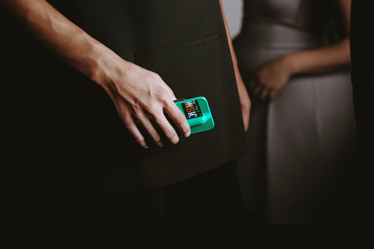 A woman standing at the entrance to a slot hall tapping a password into her phone, the lit cabinets of the floor out of focus behind her